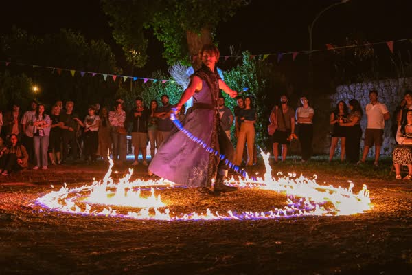 Cerchio di fuoco acceso a terra con la performer al centro, Atella Sound Circus 2023