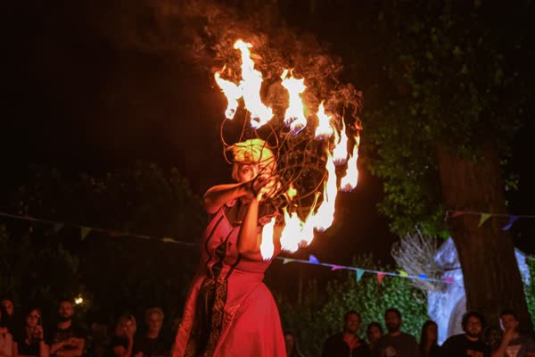 Fiamme vicine al viso della performer in abito rosso, Atella Sound Circus 2023