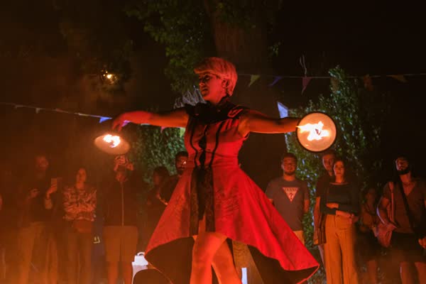 Performer in abito rosso con due fiamme tese ai lati, Atella Sound Circus 2023